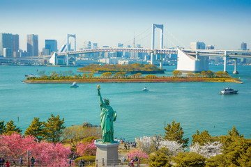 Cherry blossoms bloom in Odaiba.View of Tokyo Bay. Beautiful replica of the Statue of Liberty in Odaiba Bay from Japan.View of Odaiba in Japan. - obrazy, fototapety, plakaty