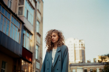 A blonde curly girl near against the background of the city