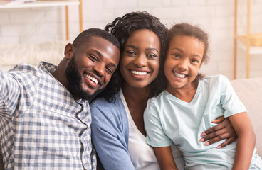 Smiling black man taking selfie with his wife and daughter