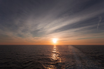 Reflection of dreamy sunset over the sea and wake left by a cruise ship, Adriatic sea, Italy