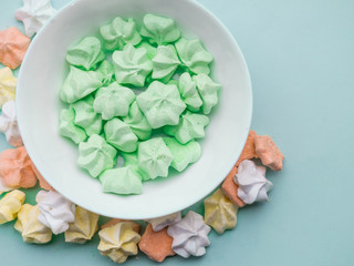 Ceramic bowl full of colorful merengues at pastel mint background