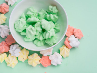 Ceramic bowl full of colorful merengues at pastel mint background