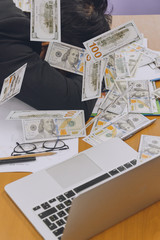 businessman slepping with heap of dollar money in office