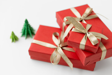 winter holidays, new year and celebration concept - red gift boxes and origami christmas trees on white background