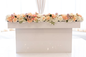 The groom and bride table near large bright windows and decorated with beautiful natural flowers
