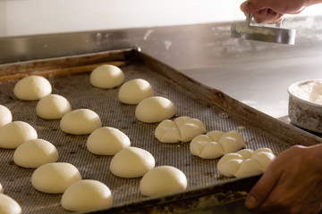 Fresh raw dough in product line. Cooks roll the dough for baking, pieces of raw dough on a metal board