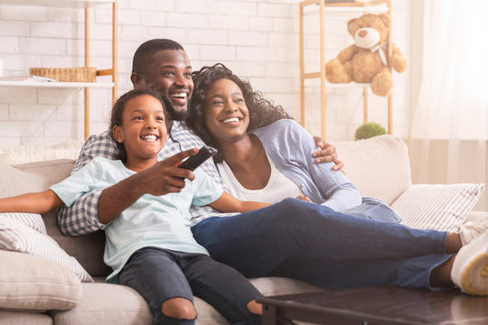 Happy black family relaxing and watching tv at home