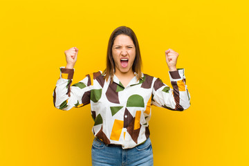 latin american woman shouting aggressively with an angry expression or with fists clenched...