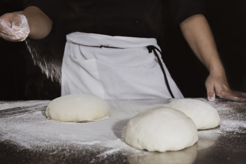 Chef prepares the dough with flour to make a pizza.