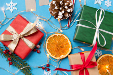 winter holidays, new year and christmas concept - gift boxes, garland lights and decorations on blue background