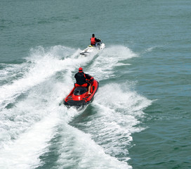 Two speeding jet skiers leaving wake trails