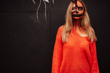 Young blonde girl with halloween face art posing outdoor.  Helloween celebration concept.