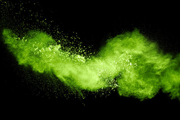 Green yellow dust particles explosion on black background. Powder dust splash.