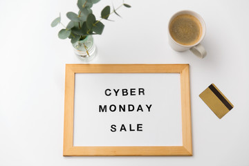 shopping and marketing concept - white magnetic board with cyber monday sale words, credit card and cup of coffee on table