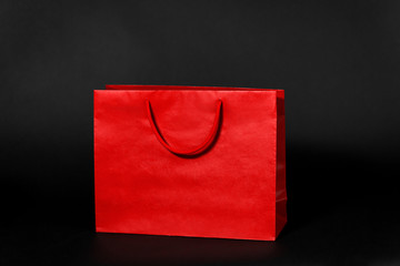 sale, consumerism and outlet concept - red shopping bag on black background