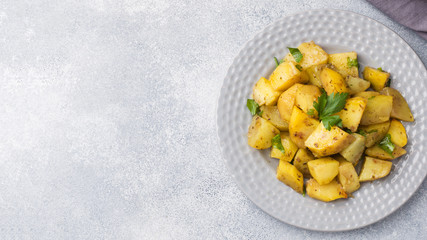 Baked potatoes with spices and herbs on a plate. Copy space.