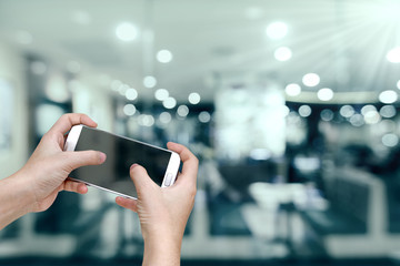 hand holding mobile smart phone with restaurant blur background,vintage effect style