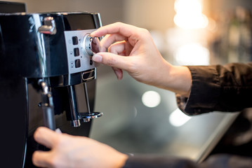 Male barista hand turning button on coffee machine in the kitchen. Making coffee concept