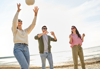 volleyball, leisure games and people concept - happy friends playing with ball on beach in summer