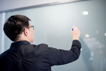 Young Asian businessman writing on empty whiteboard in meeting room or conference room. Business presentation concept