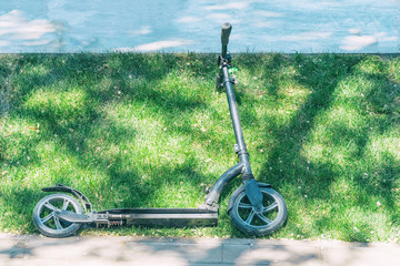 Children's scooter of black color on the green grass
