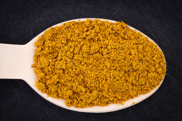 curry spices in spoon on dark background. Top view