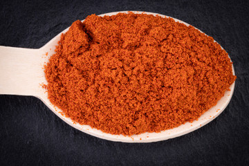 paprika spices in spoon on dark background. Top view