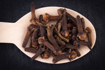 clove spices in spoon on dark background. Top view