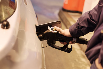 Male hand refilling the car with fuel on a filling station.