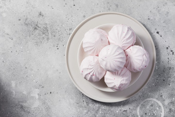 Pink marshmallows with blackcurrants on a plate. Light gray background. Space for text	