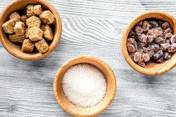 lumps of sugar with bowls sweet set on light table background top view