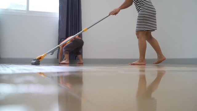Asian boy about 3 year and 8 months help his mother doing chore by mop the house floor with cloth
