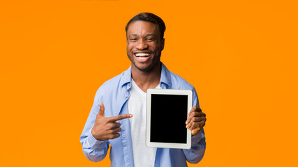Black Guy Pointing Finger At Empty Tablet Screen, Orange Background