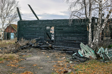 Fototapeta premium Burnt wooden house. Destroyed roof and windows, charred walls.
