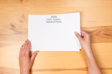 Obraz premium New year Concept - 2020 number and text on notepad and female hands of copy background. top view