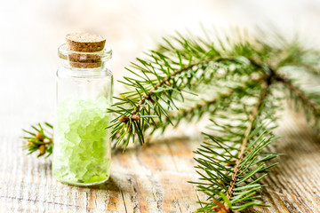 cosmetic spruce salt in bottles with fur branches on wooden table background