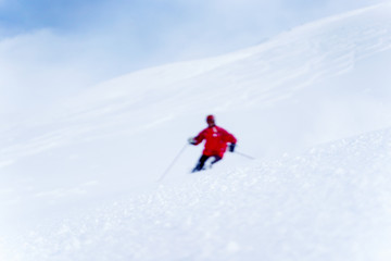 Naklejka na ściany i meble Defocused photo of sporting man skiing on snowy slope.
