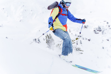 Fototapeta na wymiar Photo of sports man in multi-colored jacket skiing