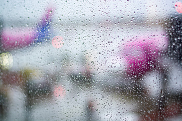 Travel in bad weather conditions concept background with water drops on window with blurred view on airplanes