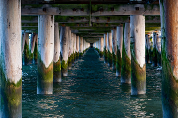 View on sea or ocean water onder old wooden pier or bridge