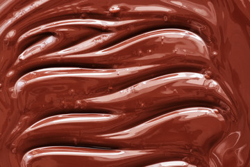 Texture of liquid molten chocolate, wave pattern. Shiny silky chocolate background.
