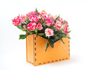 Bouquet of pink roses is in wooden box on a white background. Flowers are horizontal close-up