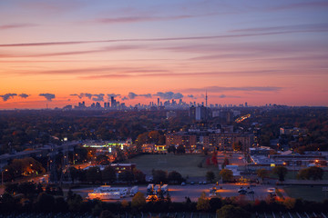 Beautiful pink yellow purple morning sky clouds in Toronto city, Canada. Rays of early rising sun. Landscape aerial top view with urban street. Twilight in Canadian metropolia at sunrise or sunset.