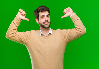 young businessman feeling proud, arrogant and confident, looking satisfied and successful, pointing...