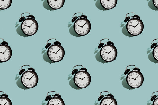 Many black classic style alarm clock isolated on green background