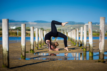 Yogui girl practicing Vrischikasana, or the Scorpion Pose variations, on the beach, Strait Natural...
