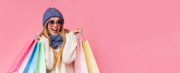 Excited girl in knitted hat and sunglasses with shopping bags