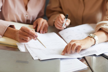 Close-up of business partners working over business report in team at the table at office