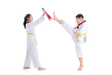 Two young asian children having taekwondo training ,one boy kicking while other one girl holding kick target over white background.