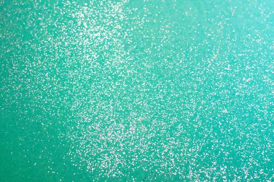 Silver glitter on a mint background. Blurry glitter texture. Sequin texture.